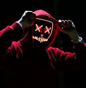 A spooky illuminated mask figure with a red hoodie in a dark setting, perfect for Halloween themes.