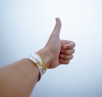 A hand giving a thumbs up gesture symbolizes approval and positivity.